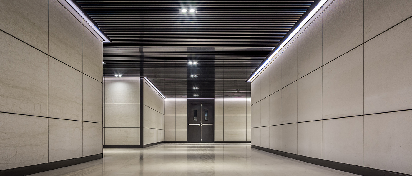 Modern commercial building lobby with professional LED linear lighting installation and black ceiling grid commercial electrical lighting services