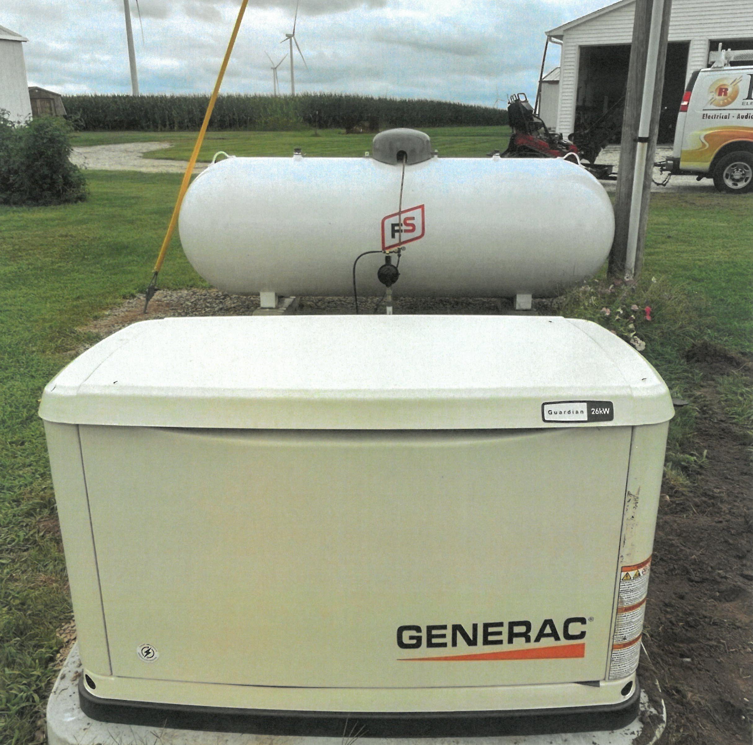 Generac residential standby generator installed on concrete pad beside home with propane tank in background in rural residential setting